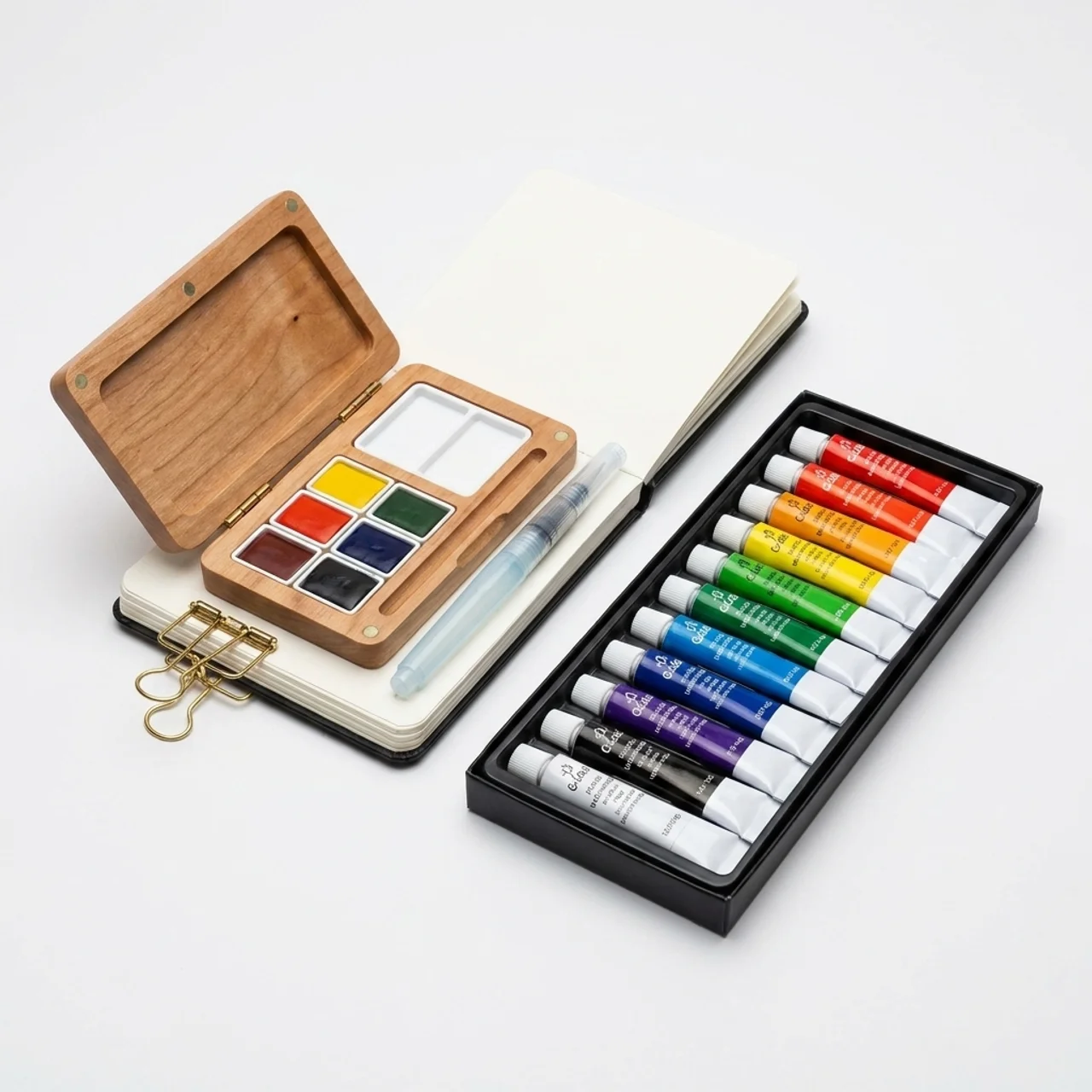 Carried Canvas mini travel watercolor set contents: 12 watercolor tubes, walnut grid palette box, sketchbook, water brush pen and brass binder clips